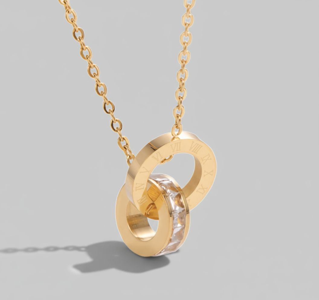 A gold-plated stainless steel necklace with a looped pendant adorned with sparkling diamonds and engraved with Roman numerals.