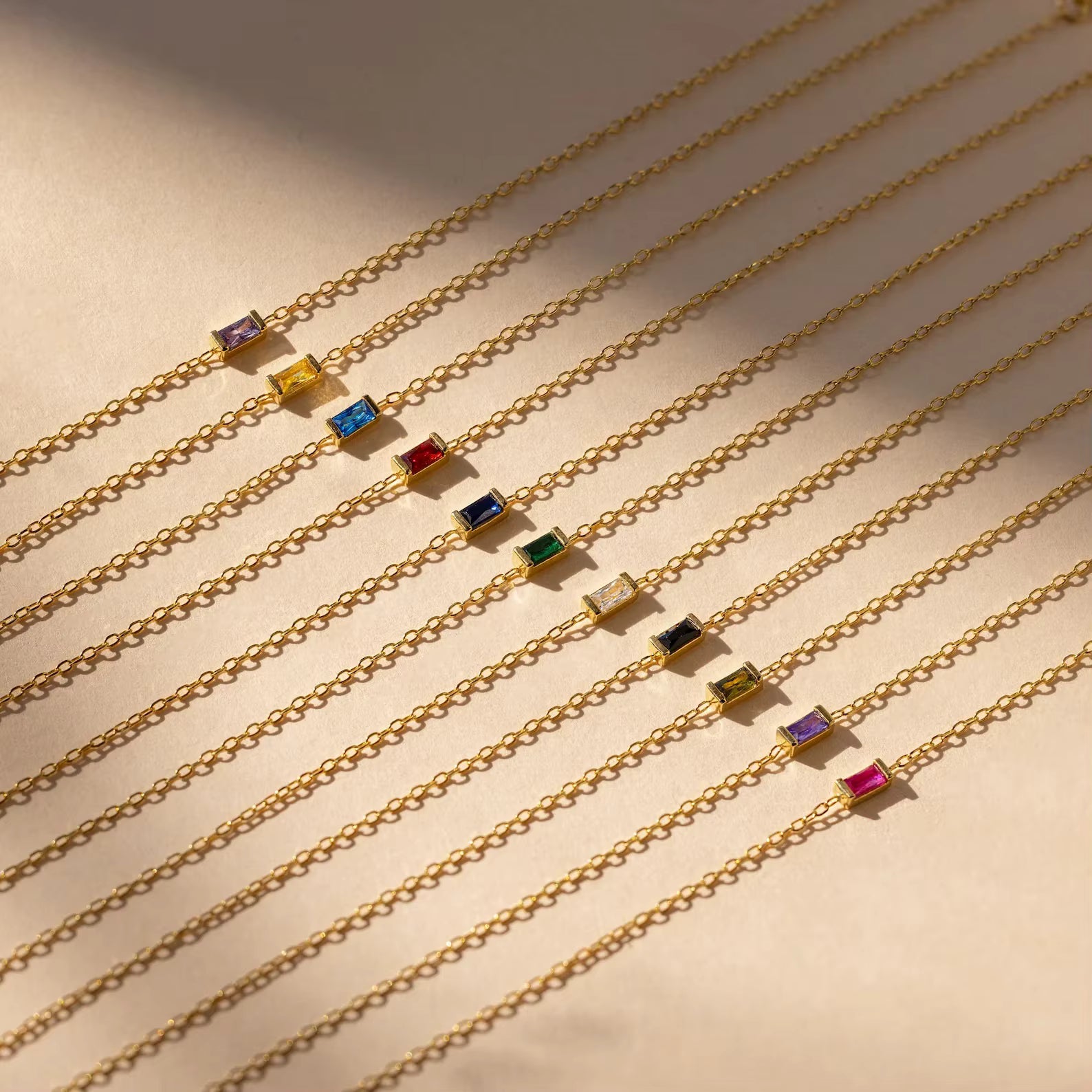 Gold chains with colorful gemstones on a beige background